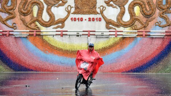 Người đàn ông đi xe máy trong trận mưa bão ở Hà Nội - Sputnik Việt Nam