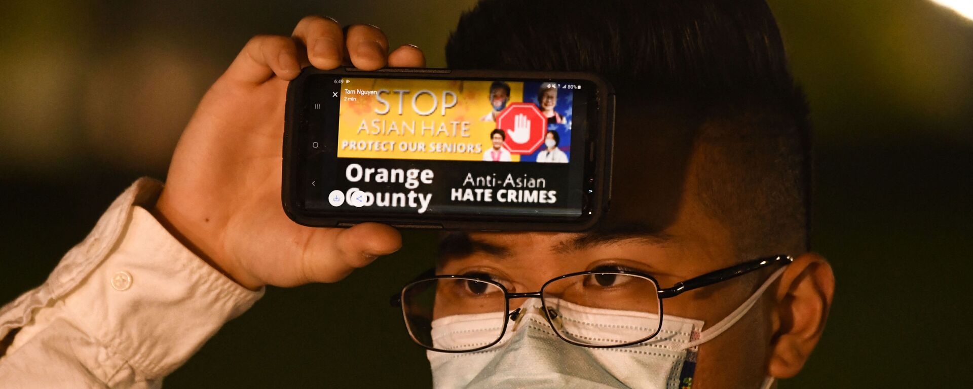 Một người đàn ông cầm điện thoại với thông điệp về tội ác căm thù đối với người Mỹ gốc Á trong một cuộc đấu trí ở Fountain Valley, California - Sputnik Việt Nam, 1920, 19.03.2021