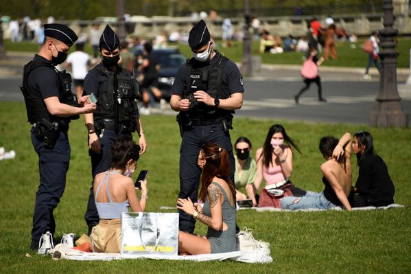 Nhân viên cảnh sát Pháp kiểm tra những người đang nghỉ ngơi trên bãi cỏ ở Paris, Pháp - Sputnik Việt Nam