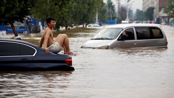Một người đàn ông ngồi trên ô tô mắc kẹt trên con đường ngập nước sau trận mưa lớn ở Trịnh Châu, tỉnh Hà Nam, Trung Quốс - Sputnik Việt Nam