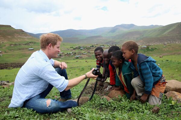 Hoàng tử Anh Harry cho trẻ em xem bức ảnh anh ấy chụp bằng máy ảnh khi đang học trường buổi tối dành cho nam sinh ở Lesotho - Sputnik Việt Nam