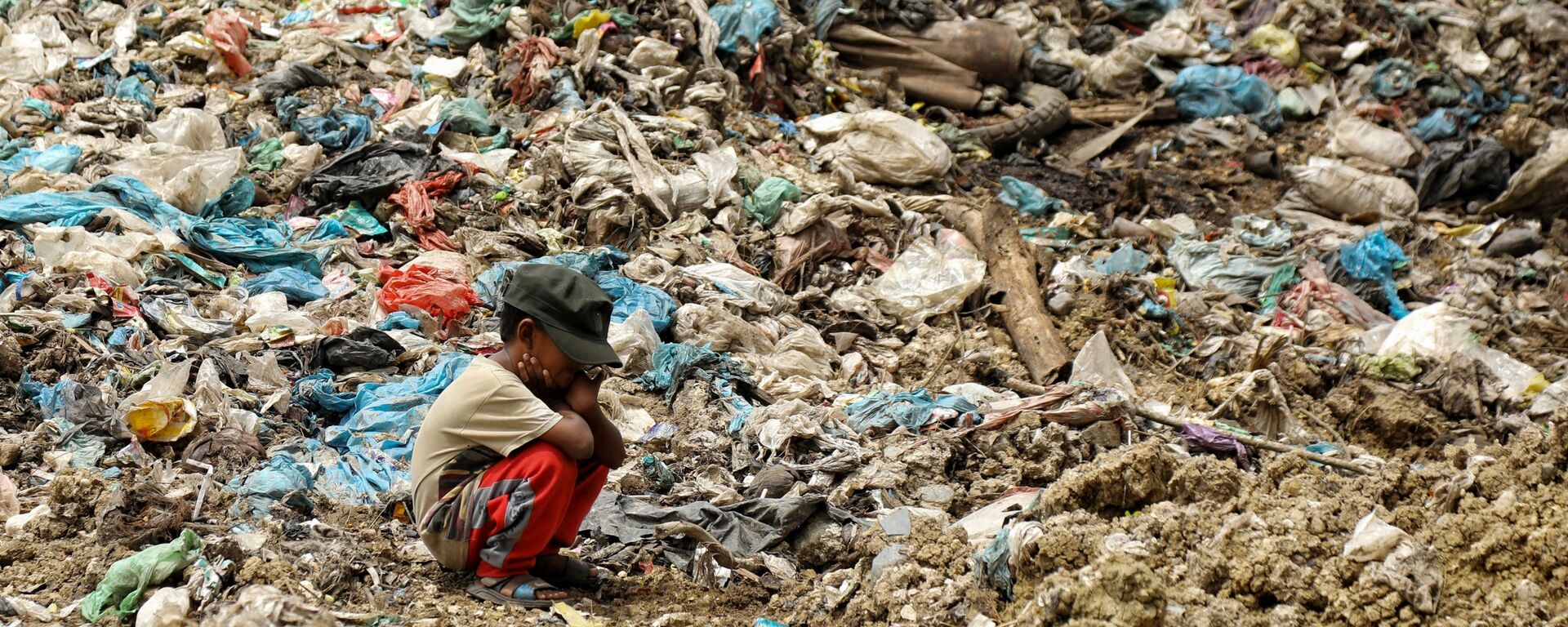 Con trai của một công nhân thu gom rác nghỉ ngơi trong khi người cha tìm kiếm đồ để bán lại tại một bãi rác ở Alue Liem, Lhokseumawe  - Sputnik Việt Nam, 1920, 23.08.2022