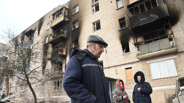 Cư dân địa phương gần một tòa nhà dân cư bị hư hại do pháo kích ở làng Donskoye, Cộng hòa Nhân dân Donetsk. - Sputnik Việt Nam
