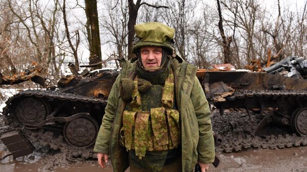 Một binh sĩ DNR gần mảnh vỡ của một chiếc xe tăng bị đắm của Lực lượng vũ trang Ukraine trên con đường gần làng Vasilyevka ở Cộng hòa Nhân dân Donetsk  - Sputnik Việt Nam