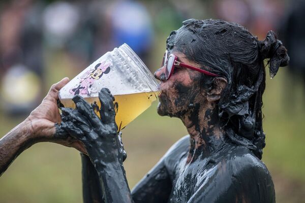 Người phụ nữ tham gia lễ hội bùn &quot;Bloco da Lama&quot; uống bia ở Paraty, bang Rio de Janeiro, Brazil - Sputnik Việt Nam