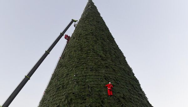 Công nhân hóa trang thành ông già Noel lắp đặt cây thông chính của thành phố, cao 55 mét (cao nhất ở Nga) trong nhiệt độ -20 độ C ở Krasnoyarsk. - Sputnik Việt Nam