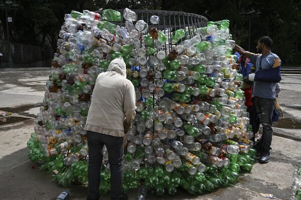 Các thành viên của tổ chức phi lợi nhuận Oko Spire dựng cây thông Noel từ 15.000 chai nhựa rỗng trên đường phố Caracas, Venezuela. - Sputnik Việt Nam