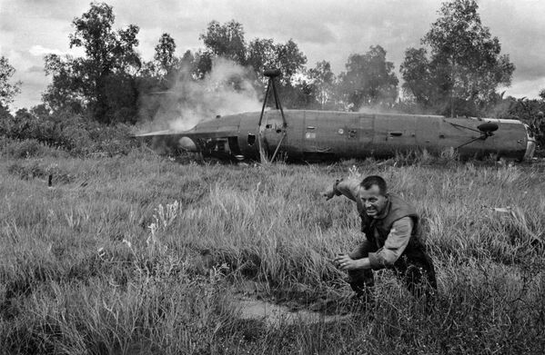 Lính Mỹ chạy xa khỏi chiếc trực thăng CH-21 Shawnee rơi ở miền Nam Việt Nam. - Sputnik Việt Nam