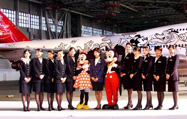 Các tiếp viên hàng không Japan Airlines (JAL) tạo dáng với các nhân vật chuột Mickey và Minnie trước máy bay phản lực JAL khổng lồ tại nhà chứa máy bay của Sân bay Quốc tế Tokyo ở Haneda, Nhật Bản, năm 2001. - Sputnik Việt Nam
