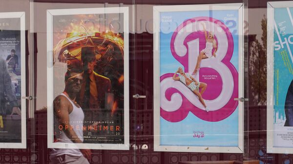 A man's reflection appears walking past advertisements for the films Oppenheimer, from left, and Barbie, on Thursday, July 20, 2023, at the Landmark Theater in Los Angeles.  - Sputnik Việt Nam