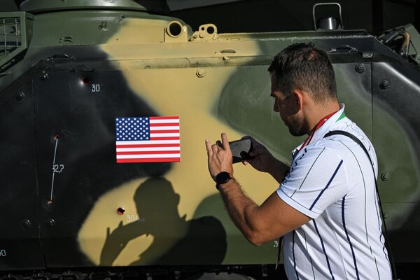 Người đàn ông chụp ảnh các vết đạn trên xe bọc thép thu giữ được trưng bày trong khuôn khổ Diễn đàn Kỹ thuật-Quân sự Quốc tế Army-2023 tại Trung tâm Triển lãm và Hội nghị Patriot - Sputnik Việt Nam