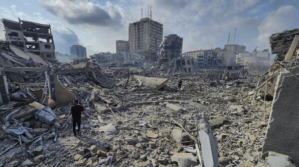 Người Palestine đi qua đống đổ nát của các tòa nhà bị phá hủy trong cuộc không kích của Israel tại thành phố Gaza, ngày 10 tháng 10 năm 2023 - Sputnik Việt Nam