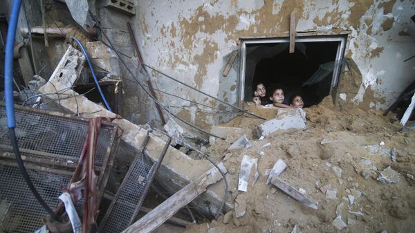 Trẻ em Palestine nhìn từ dưới đống đổ nát của một tòa nhà bị phá hủy do các cuộc không kích của Israel ở Rafah, Gaza - Sputnik Việt Nam