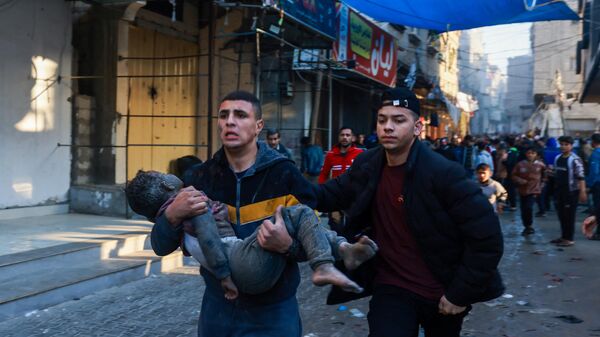 Một người Palestine mang theo một cậu bé bị thương sau khi Israel tiếp tục ném bom ở Rafah, phía nam Dải Gaza - Sputnik Việt Nam