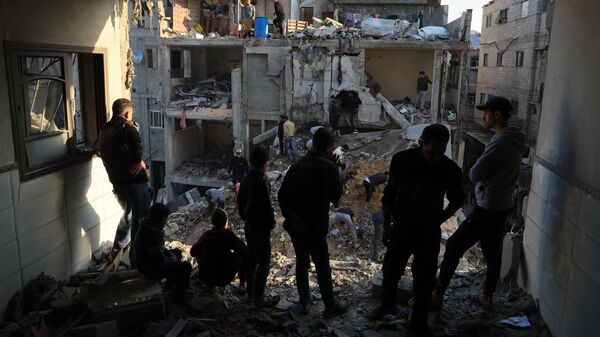 Người Palestine quan sát những tàn phá xung quanh các tòa nhà dân cư sau khi Israel tấn công trại tị nạn Rafah - Sputnik Việt Nam