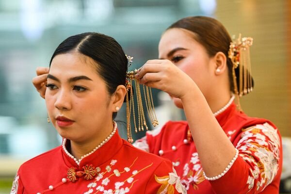 Một nhân viên đeo phụ kiện tóc kiểu Trung Quốc cho đồng nghiệp của mình tại trung tâm mua sắm ở khu phố Tàu, Manila. - Sputnik Việt Nam