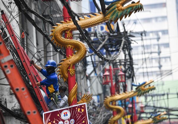 Các công nhân sửa chữa đường dây cáp bên cạnh những đèn đường hình con rồng ở khu phố Tàu (China Town) của thủ đô Manila trước Tết Nguyên đán. - Sputnik Việt Nam