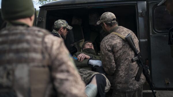 Украинские военные перекладывают раненого сослуживца в автомобиль - Sputnik Việt Nam
