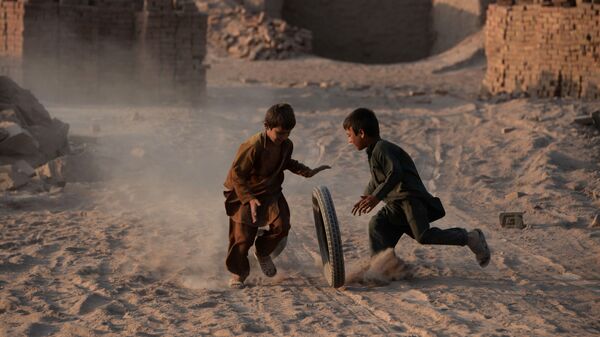 Các trẻ em Afghanistan chơi với bánh xe trên con đường cát bụi ở ngoại ô Jalalabad - Sputnik Việt Nam