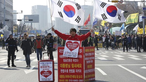 Мужчина держит национальные флаги Южной Кореи в поддержку президента Пак Кын Хе - Sputnik Việt Nam