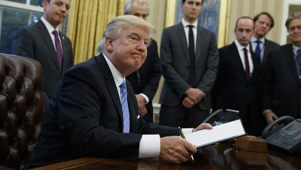 President Donald Trump looks up after signing the final of three executive orders, Monday, Jan. 23, 2017, in the Oval Office of the White House in Washington. (AP Photo/Evan Vucci) - Sputnik Việt Nam