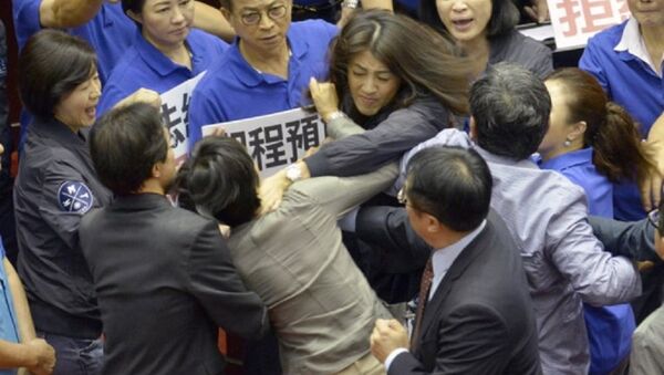 Nghị sĩ Hsu Shu-hua (áo đậm hơn, Quốc dân đảng) cố bóp cổ nghị sĩ Chu Yi-ying (đảng Dân tiến) trong khi các đồng nghiệp lao vào để ngăn cản người. - Sputnik Việt Nam