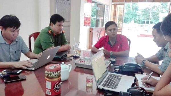 Trung úy Nguyễn Văn Thành (mặc áo đỏ) đang trả lời  báo chí về  việc xử lý vi phạm đối với chiếc xe chở trung tướng Võ Văn Liêm. - Sputnik Việt Nam