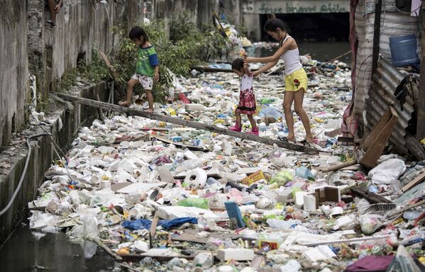 Cư dân ngôi nhà đi trên tấm ván gỗ bắc qua đống rác ở Manila, Philippines - Sputnik Việt Nam