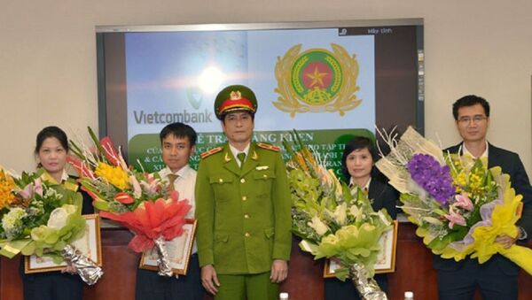 Thiếu tướng Nguyễn Thanh Hóa (đứng giữa), Cục trưởng Cục Cảnh sát Phòng chống tội phạm công nghệ cao trao Giấy khen cho 4 cá nhân thuộc Vietcombank. - Sputnik Việt Nam