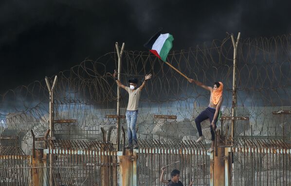 Người biểu tình Palestine trên hàng rào kim loại ở biên giới ven biển giữa Israel và Dải Gaza - Sputnik Việt Nam