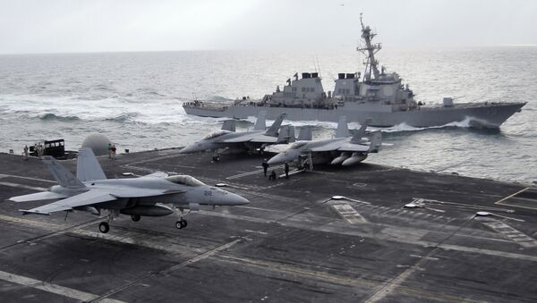 This file photo taken on Monday, Feb. 13, 2012 shows a U.S. F-18 fighter jet, left, land on the Nimitz-class aircraft carrier USS Abraham Lincoln (CVN 72) as a U.S. destroyer sells on alongside during fly exercises in the Persian Gulf - Sputnik Việt Nam