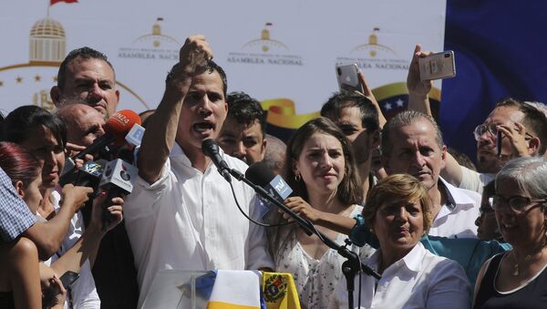 Juan Guaido, president of National Assembly, shows marks on his wrists, which he says are from handcuffs, to supporters at a rally in Caraballeda, Venezuela, Sunday, Jan. 13, 2019. The new head of Venezuela's increasingly defiant congress was pulled from his vehicle and briefly detained by police Sunday, a day after the U.S. backed him assuming the presidency as a way out of the country's deepening crisis. Guaido's wife Fabiana Rosales stands next to him, right. (AP Photo/Fernando Llano) - Sputnik Việt Nam