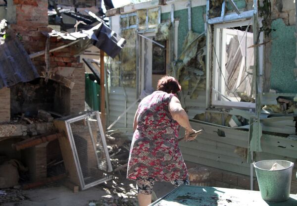 Người phụ nữ dọn rác trong sân tòa chung cư ở Donetsk sau vụ pháo kích - Sputnik Việt Nam