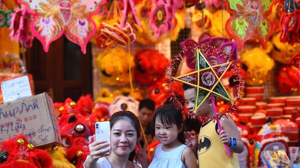 Một người phụ nữ Việt Nam chụp ảnh tự sướng cùng hai con ở khu phố cổ Hà Nội trước thềm Lễ hội Trung thu sắp tới. - Sputnik Việt Nam